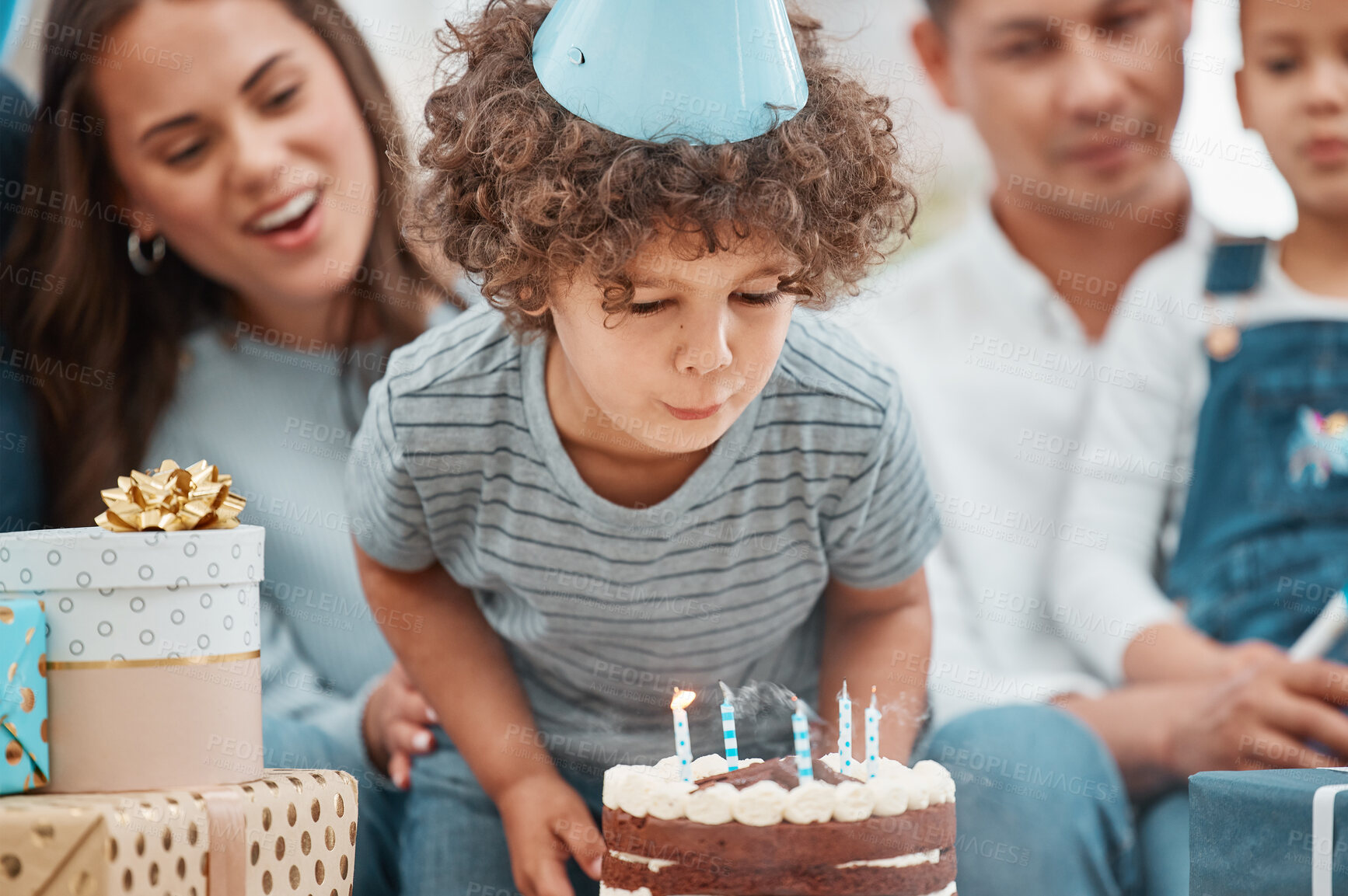 Buy stock photo Boy, blowing candles and celebrate birthday in home, happy and child in party hat for milestone. Male person, bonding and family to support kid at special event, growth development and flame on cake