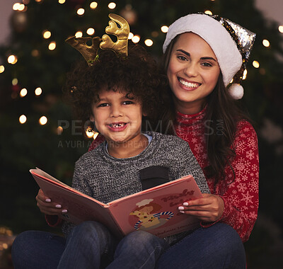 Buy stock photo Shot of a young mother and son reading a book during Christmas time at home