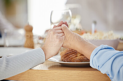 Buy stock photo Shot of two unrecognizable people holding hands at the dinner table at home