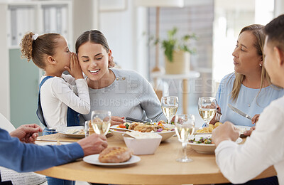 Buy stock photo Shot of a little girl whispering a secret in her mothers ear while having lunch with her family at home