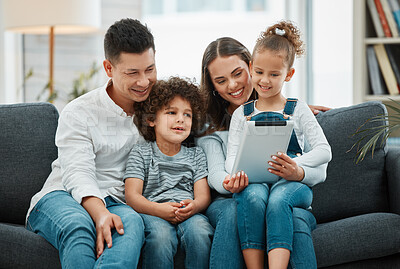 Buy stock photo Shot of a young family spending time together while using a digital tablet
