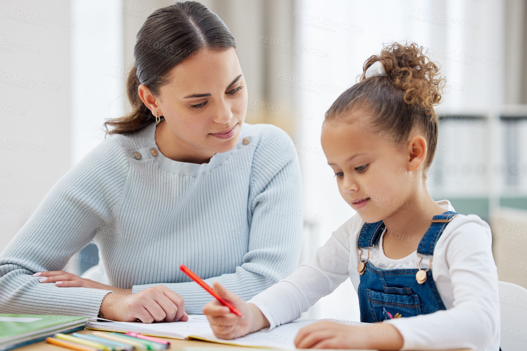 Buy stock photo Shot of a young mother helping her daughter with her homework at home