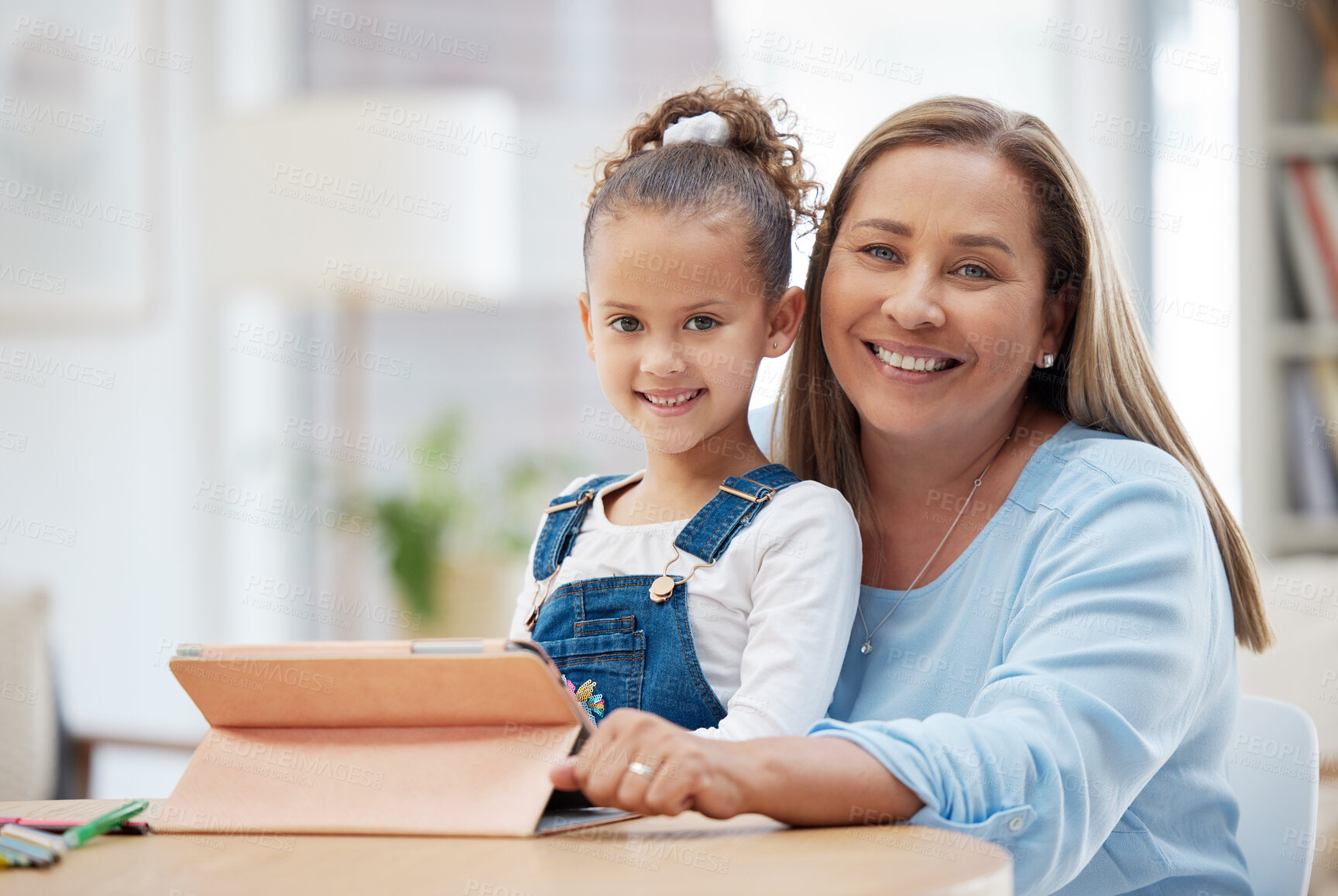 Buy stock photo Shot of a little girl and her grandmother using a digital tablet at home