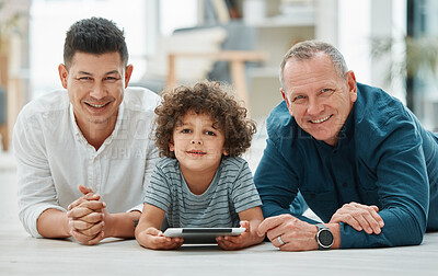 Buy stock photo Shot of a young man spending time with his father and son while using a digital tablet
