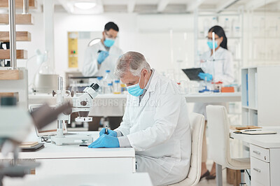 Buy stock photo Shot of a mature scientist writing notes while working in a lab