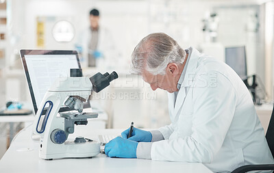 Buy stock photo Shot of a mature scientist writing notes while working in a lab