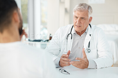 Buy stock photo Shot of a senior doctor sitting with his patient during a consultation in his clinic