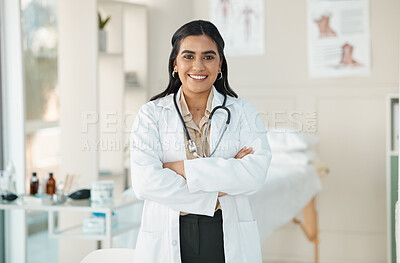 Buy stock photo Shot of an attractive young doctor standing alone in her clinic with her arms folded