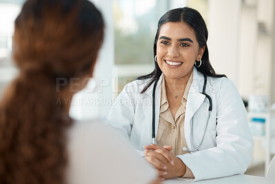 Buy stock photo Shot of an attractive young doctor sitting with her patient during a consultation in her clinic