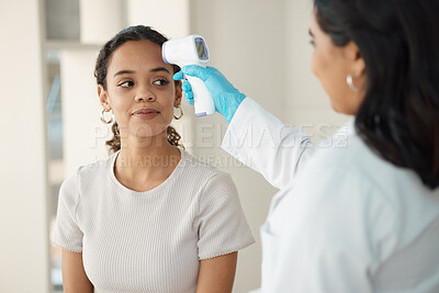 Buy stock photo Shot of a young woman sitting in the clinic and getting her temperature checked by her doctor during a consultation