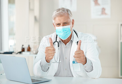 Buy stock photo Shot of a senior doctor sitting alone in his clinic and wearing a face mask while making a thumbs up hand gesture
