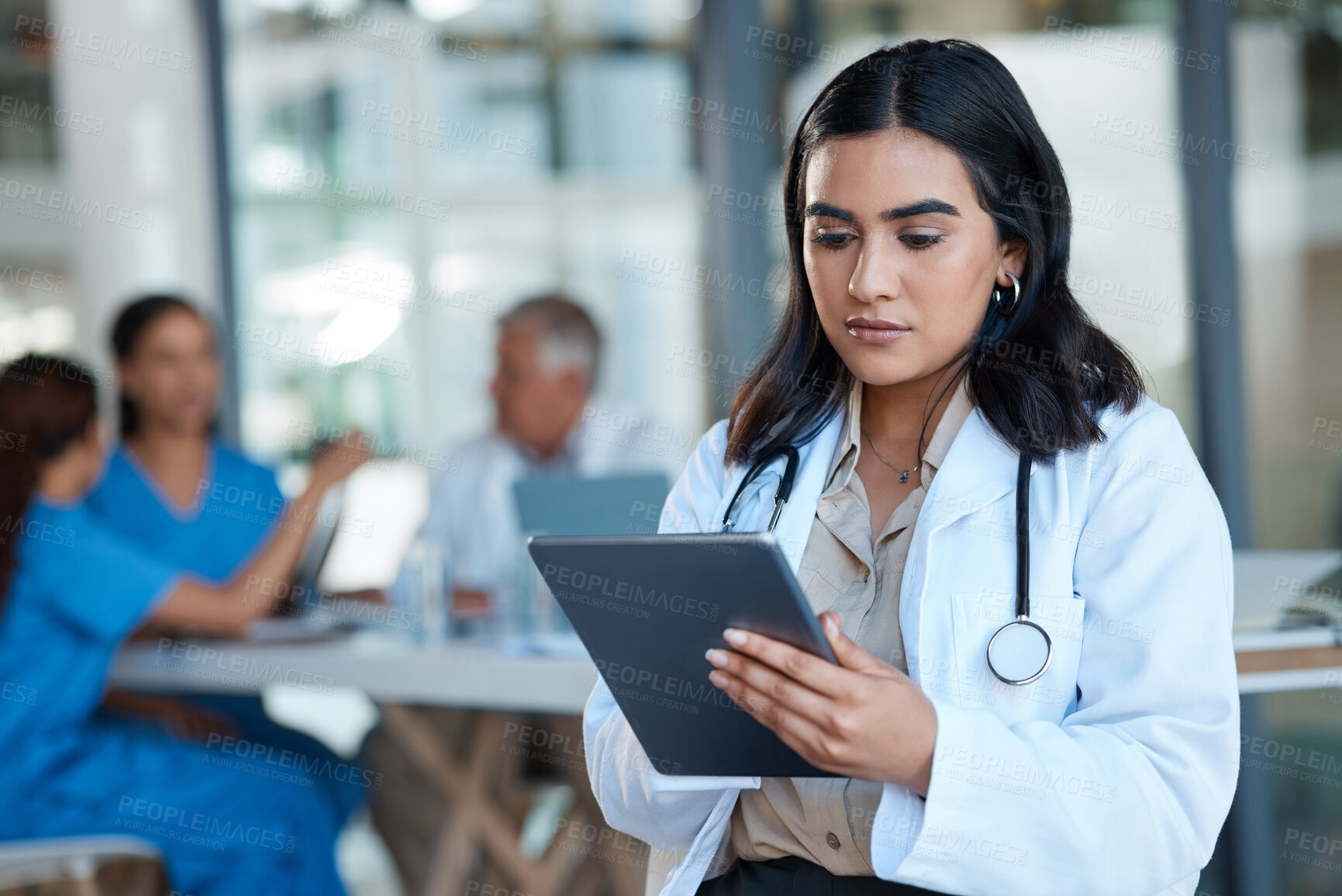 Buy stock photo Shot of a female doctor using a digital tablet during a meeting