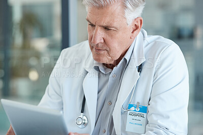 Buy stock photo Shot of a male doctor using his digital tablet in his office