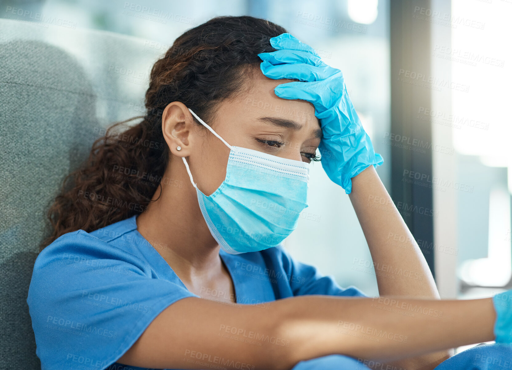 Buy stock photo Shot of a female nurse looking stressed while sitting in a hospital