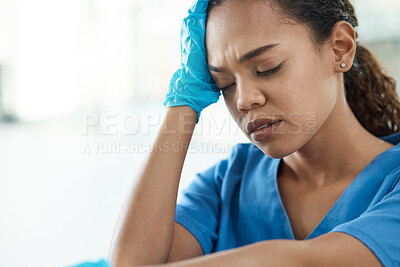 Buy stock photo Shot of a female nurse looking stressed while sitting in a hospital