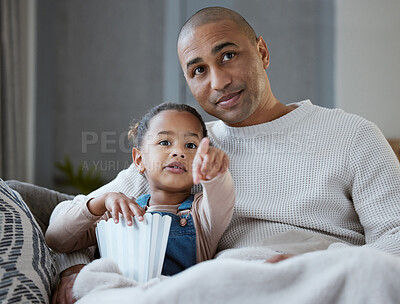 Buy stock photo Shot of a father and daughter eating popcorn while watching television together at home