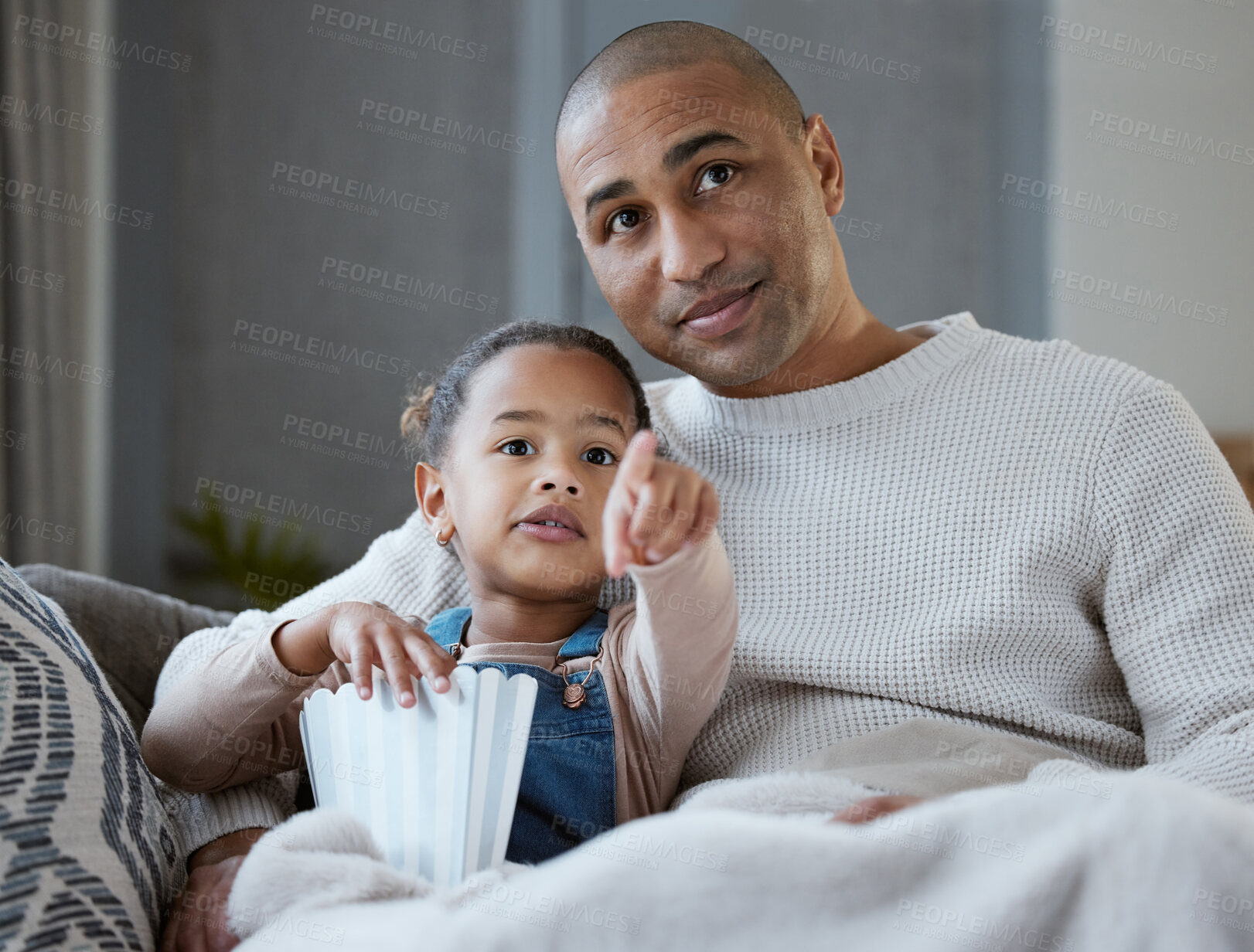 Buy stock photo Father, girl and watching tv on sofa with popcorn, point and relax with bonding, care and movies in lounge. Man, dad and daughter with eating, choice and connection in family house for film in Mexico