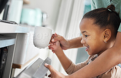 Buy stock photo Shot of a little girl putting a cup into the dishwashing machine at home with her mother