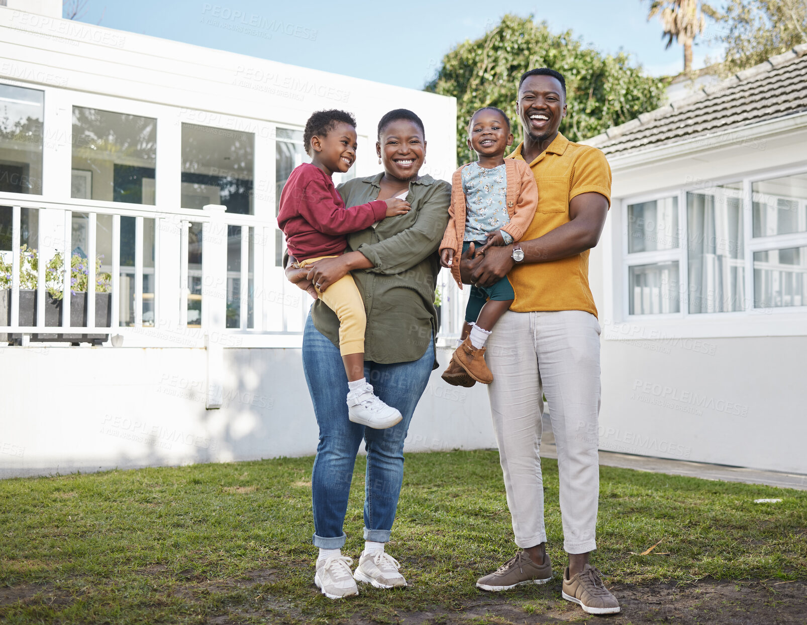 Buy stock photo Shot of a couple standing in front of a house with their two children