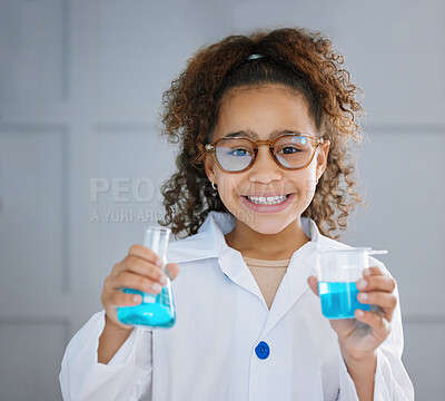 Buy stock photo Cropped portrait of an adorable little girl wearing a labcoat while holding two containers of blue liquid
