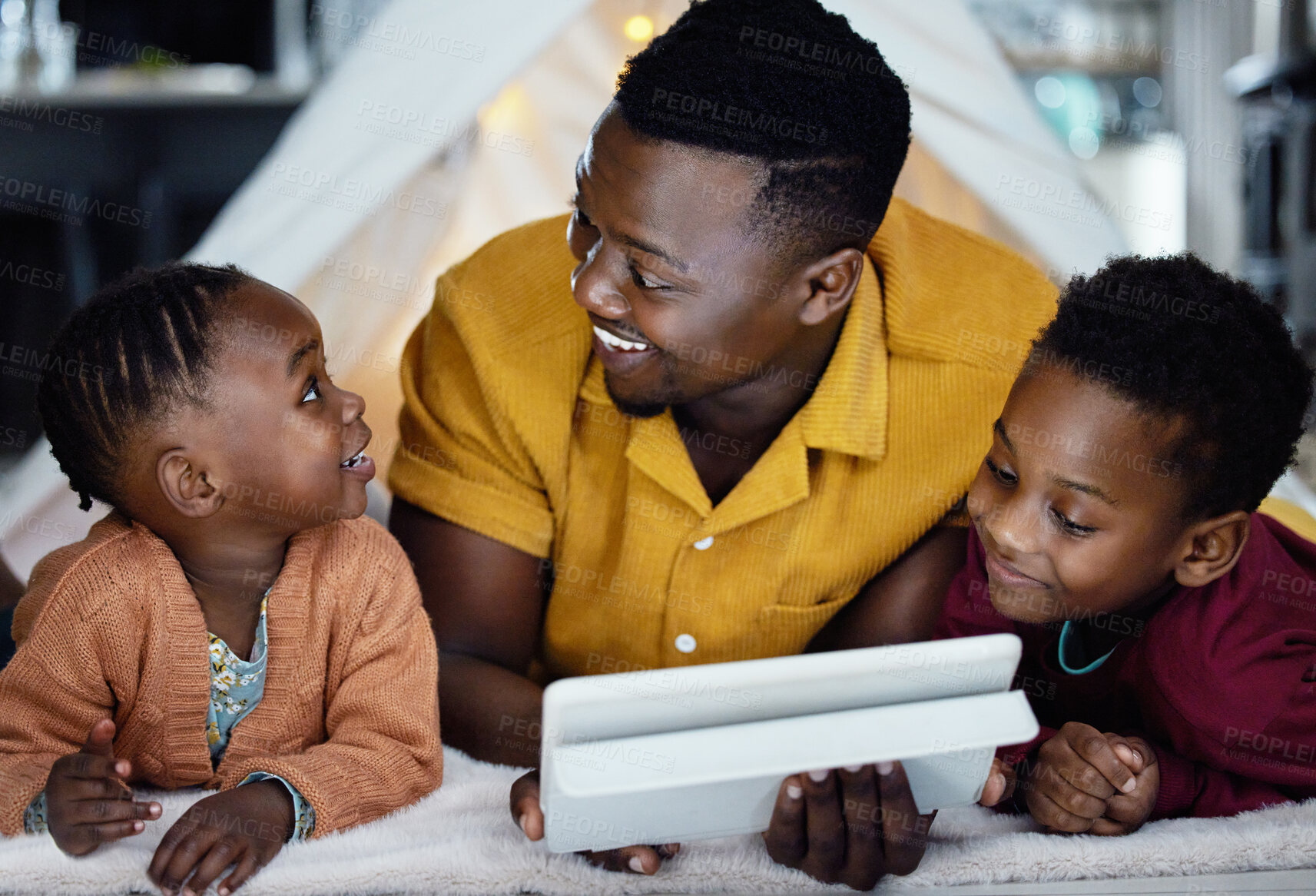 Buy stock photo Black man, smile and children relax with tablet at night for streaming story online, watch movie and bonding in tent. African, father and kids with digital for storytelling, care and love at house
