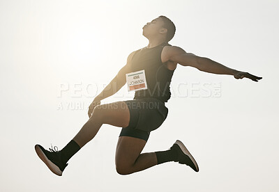 Buy stock photo Low angle shot of a handsome young man leaping high into the air during his long jump attempt