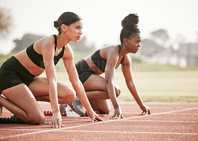 Buy stock photo Cropped shot of two attractive young female athletes starting their race on a track