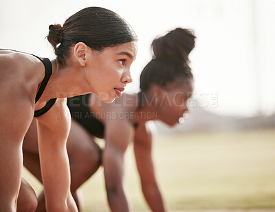 Buy stock photo Cropped shot of two attractive young female athletes starting their race on a track