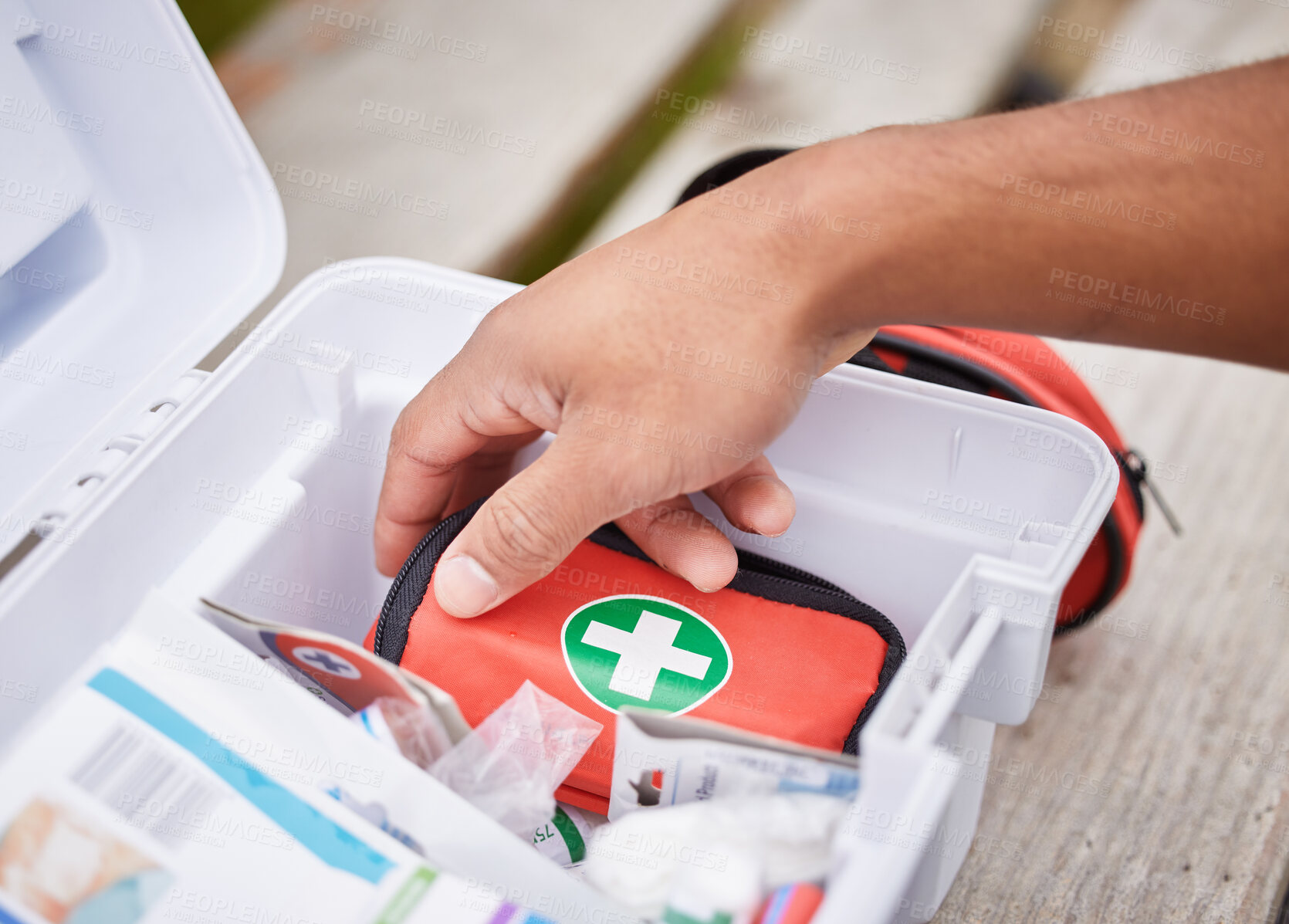 Buy stock photo High angle shot of an unrecognizable male paramedic looking in his first aid kit while standing outside