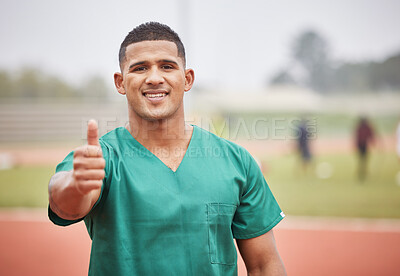 Buy stock photo Cropped portrait of a handsome young male paramedic giving thumbs up while standing on a track outside