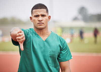 Buy stock photo Cropped portrait of a handsome young male paramedic giving thumbs down while standing on a track outside