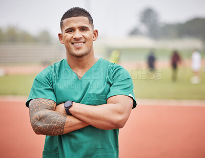 Buy stock photo Cropped portrait of a handsome young male paramedic standing with his arms folded on a track outside