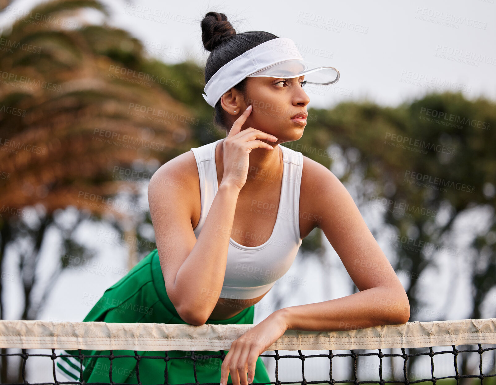 Buy stock photo Shot of a sporty young woman leaning over the tennis net