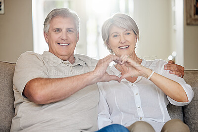 Buy stock photo Shot of a mature couple making a heart sign with their hands at home