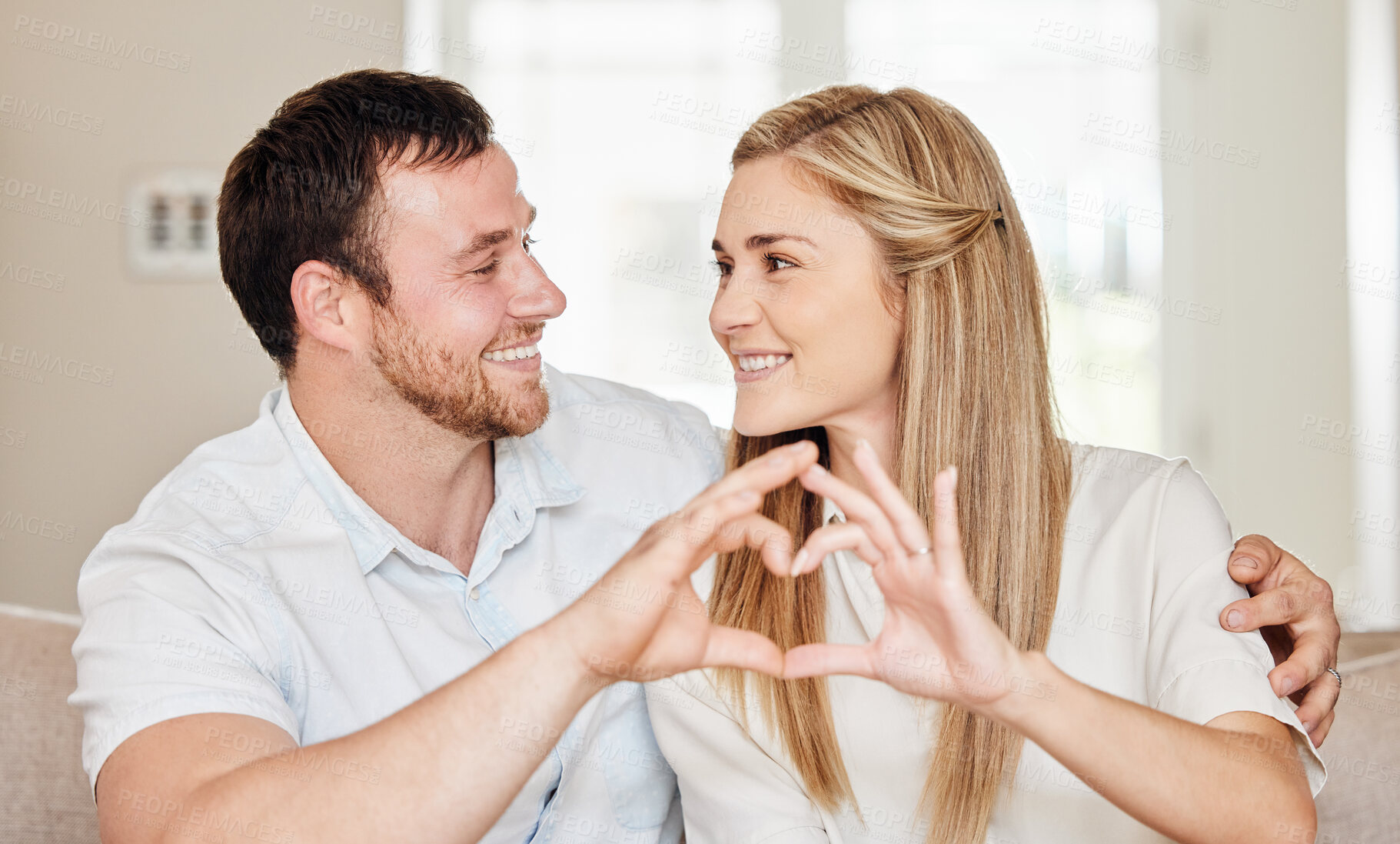 Buy stock photo Happy, hands in heart and couple on sofa for bonding, loving relationship and relax in home. Marriage, emoji and man and woman with hand sign on couch for love, affection and care in living room