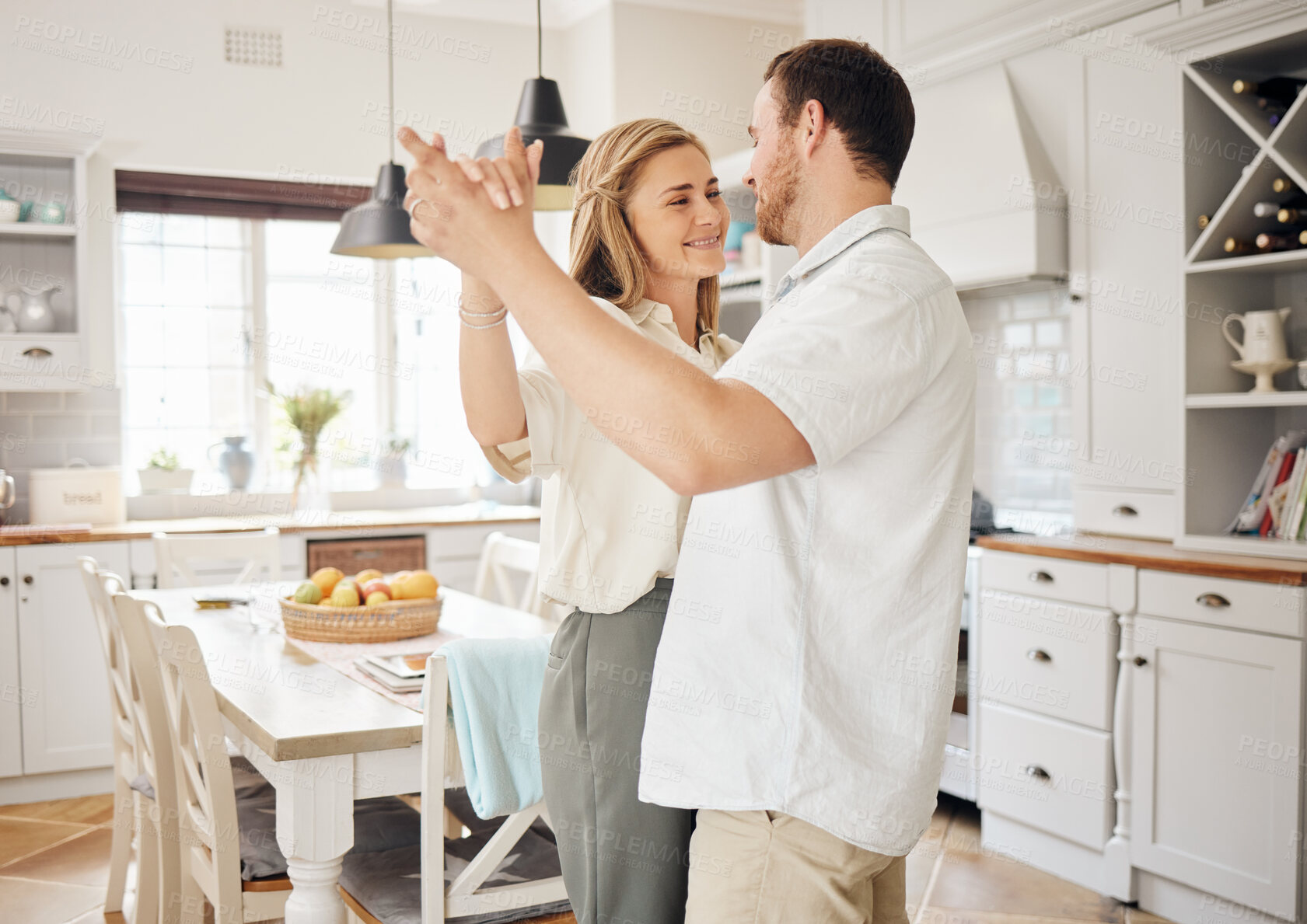 Buy stock photo Love, home and couple with smile, dancing and weekend bonding together for support in relationship. Relax, man and woman embrace in kitchen with music, holding hands and fun romance in happy marriage