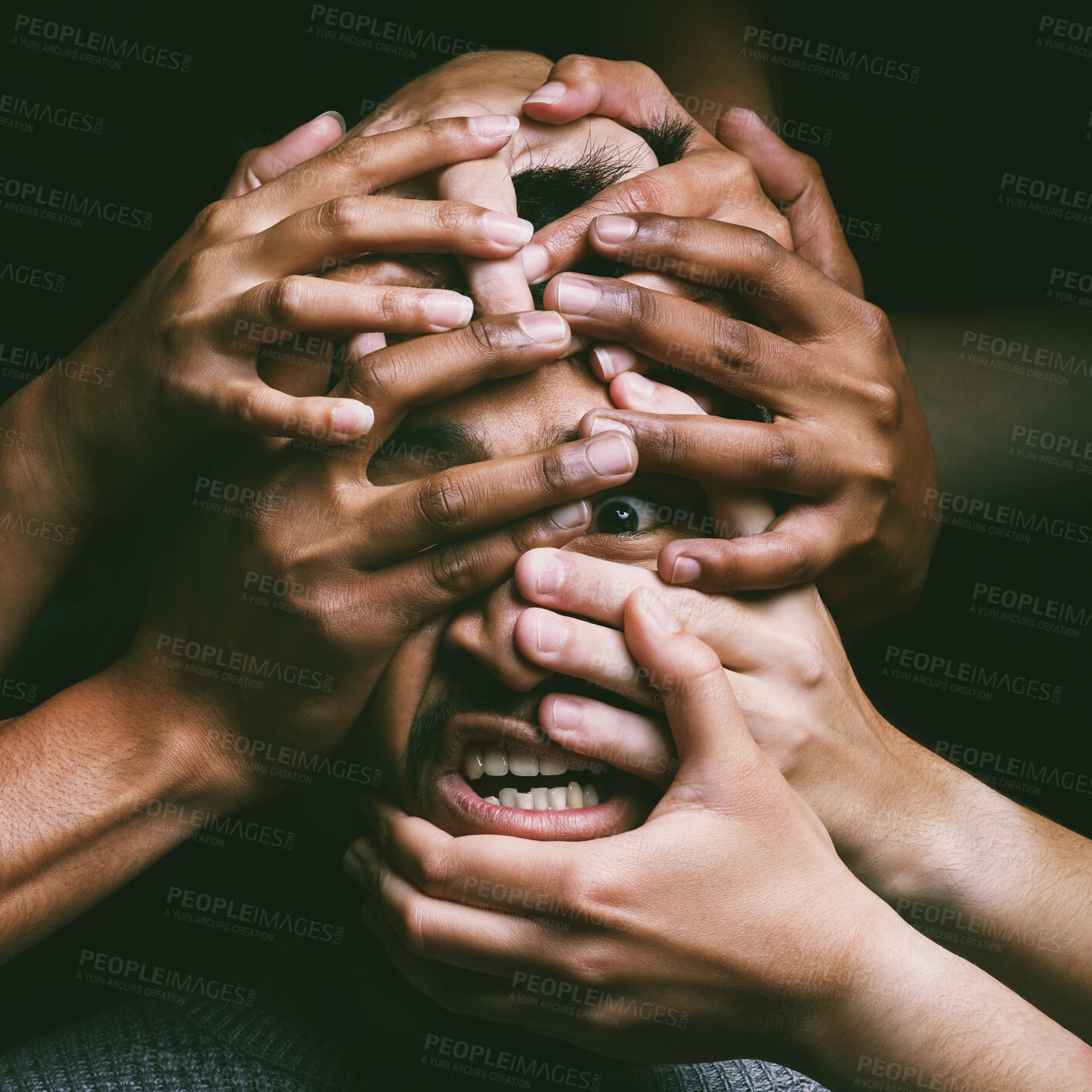 Buy stock photo Shot of hands grabbing a young man’s face against a dark background