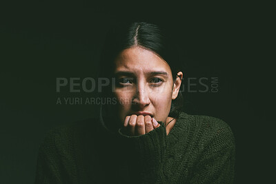 Buy stock photo Shot of a young woman looking nervous against a dark background