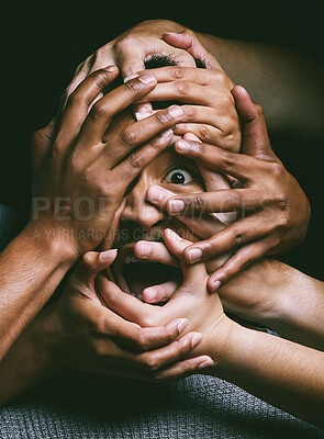 Buy stock photo Shot of hands grabbing a young man’s face against a dark background