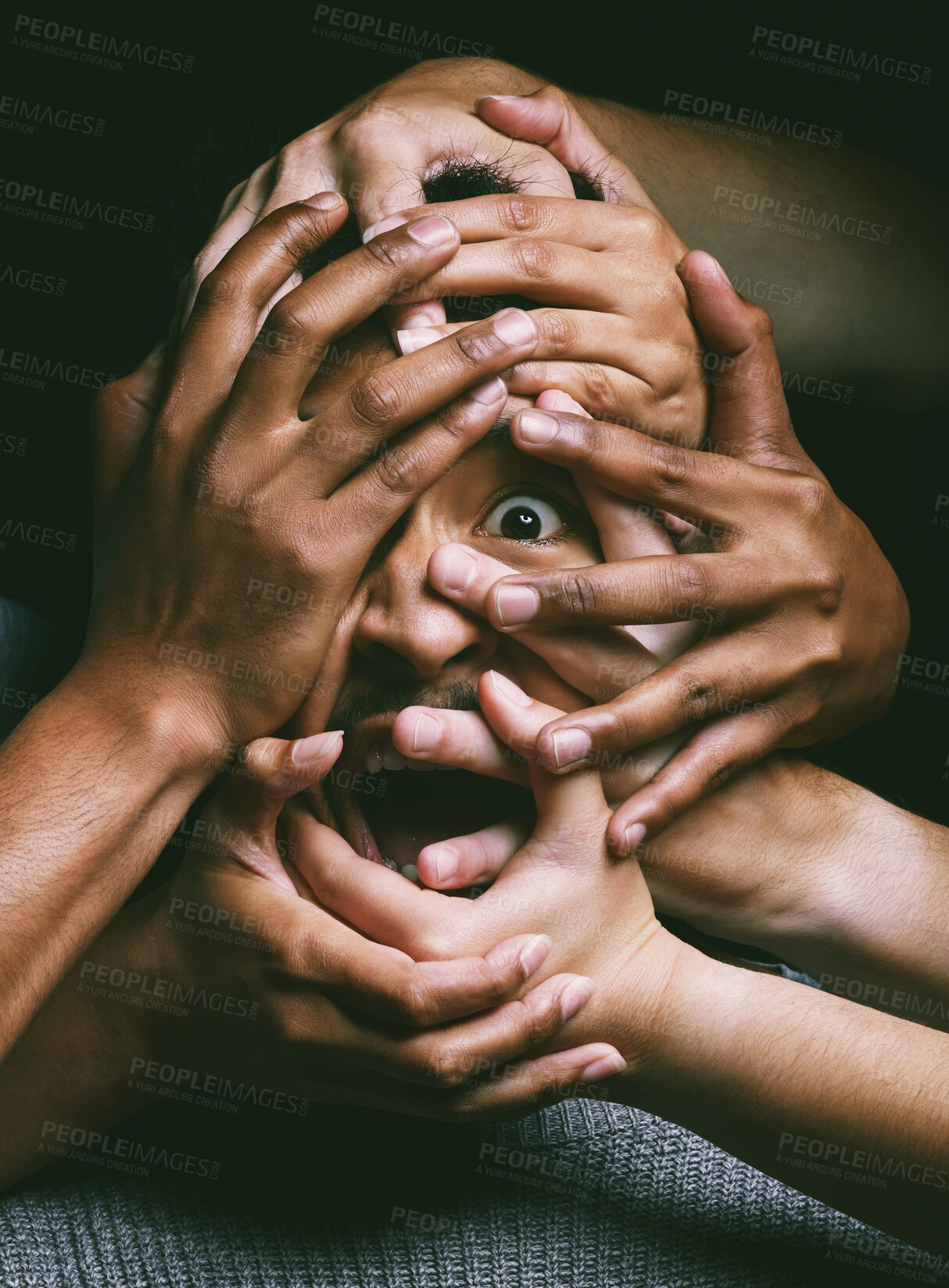 Buy stock photo Shot of hands grabbing a young man’s face against a dark background