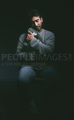 Buy stock photo Shot of a young man looking unhappy and cuddling a stuffed animal against a black background