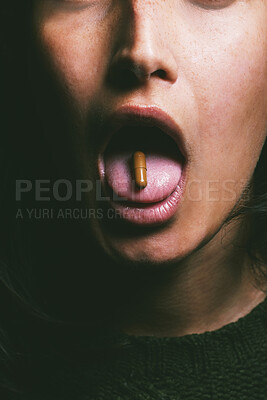 Buy stock photo Shot of an unrecognisable woman taking a pill against a dark background