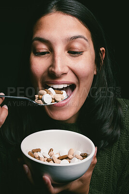 Buy stock photo Shot of a young woman eating a bowl full of pills