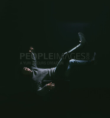 Buy stock photo Shot of a young man falling against a dark background