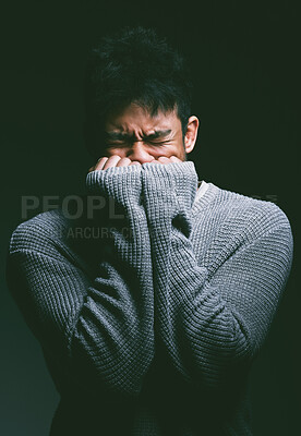 Buy stock photo Shot of a young man looking nervous against a dark background