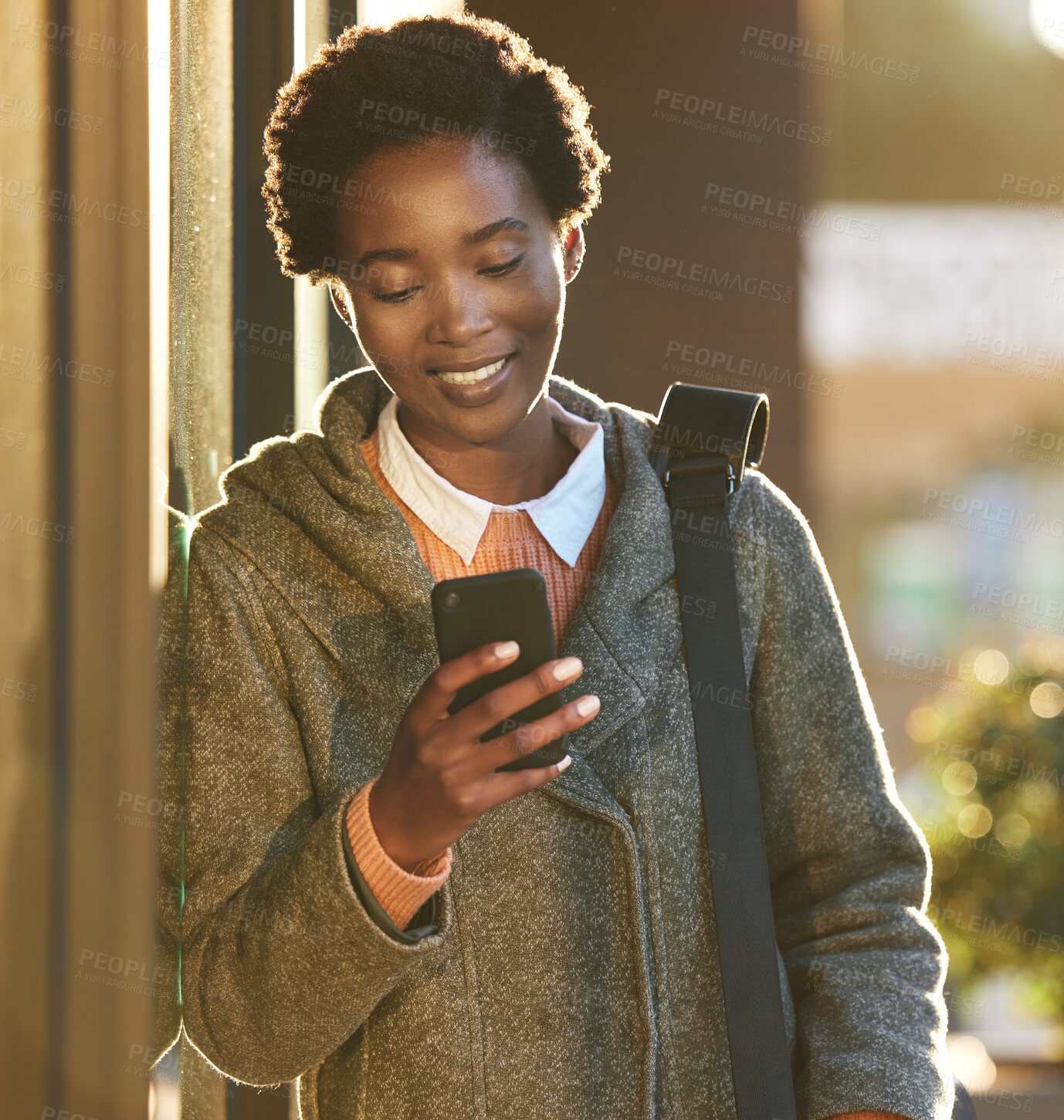 Buy stock photo Shot of a young businesswoman using a smartphone while going for a walk on a rainy day in the city