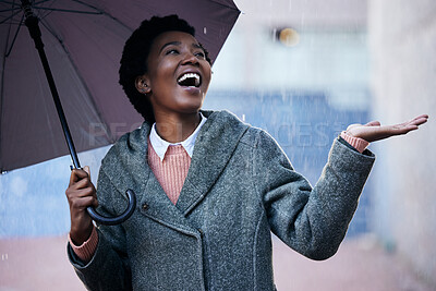 Buy stock photo Shot of a young businesswoman using an umbrella to cover with while going for a walk in the rain against an urban background