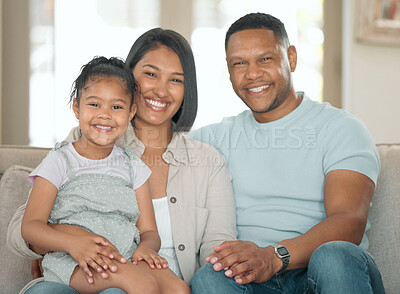 Buy stock photo Shot of a young couple sitting on their sofa at home with their daughter