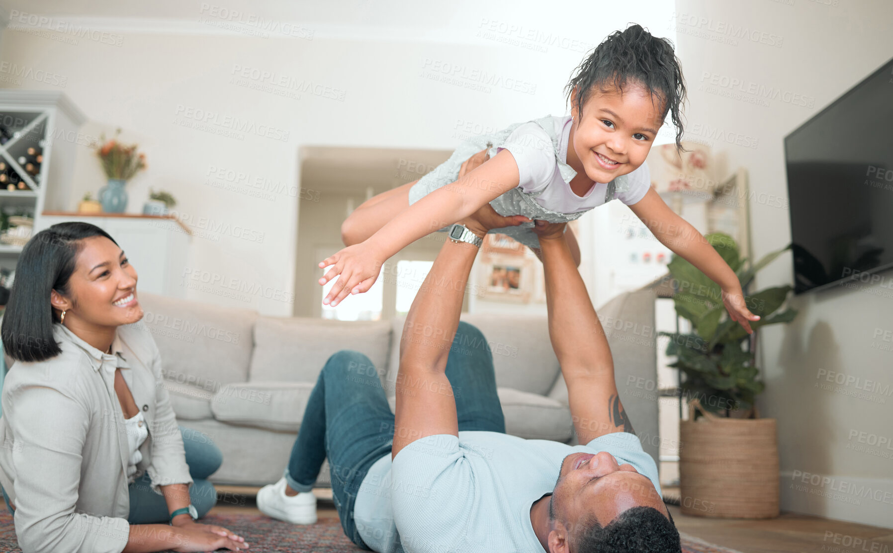 Buy stock photo Shot of an adorable little girl bonding with her parents in the living room at home