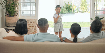 Buy stock photo Shot of an adorable little girl standing in the living room at home and singing for her family